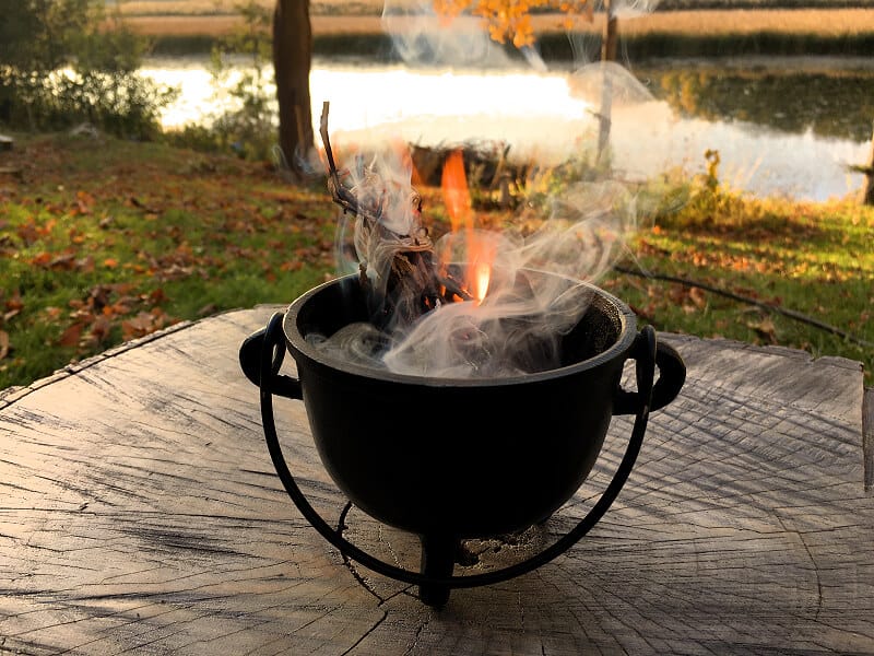 Cauldron with burning plant materials during ritual.